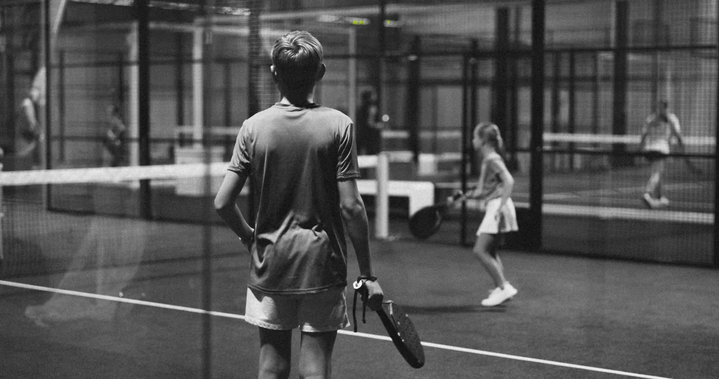 Un niño con pala, de espaldas, observa a una niña en una pista cubierta